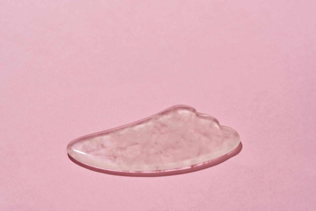 Jade Gua Sha Massage Tool in pale pink translucent stone with smooth sculpted edges and rounded massage contours