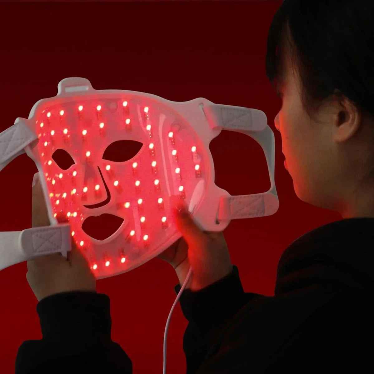 Infrared Light Therapy LED facial mask with dual handles, white plastic frame, and red LED lights for skin treatment
