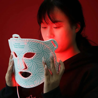 Infrared Light Therapy white plastic facial mask with blue swirling pattern and dual handles emitting red LED light